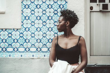 Azulejo fayanslı duvarın yanındaki afro kız.