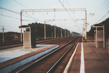 Birçok platforma ve tren yoluna sahip açık bir tren istasyonu uzaktaki bir kaybolma noktasına uzanıyor, akşam Pavino 'nun banliyö bölgesinde, Novosibirsk, Rusya, sığ alan derinliği