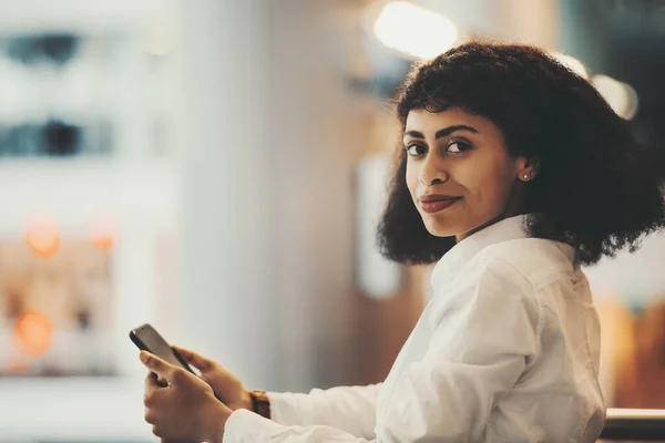 Beyaz Gömlekli Cep Telefonlu Kıvırcık Saçlı Kameraya Bakan Göz Kamaştırıcı — Stok fotoğraf