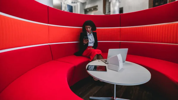 Широкоугольный Снимок Афроамериканской Предпринимательницы Сидящей Ноутбуком Смартфоном Изогнутом Круглом Красном — стоковое фото