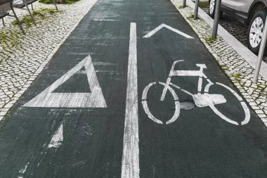 Wide-angle view of a road marking sign on asphalt on a bicycle lane and the running track, dividing line in the center, paving-stone on sides clipart