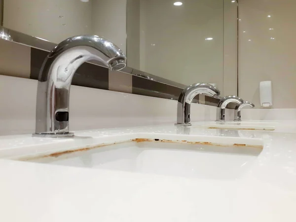 Nombreux robinets en acier dans un évier en céramique blanche — Photo