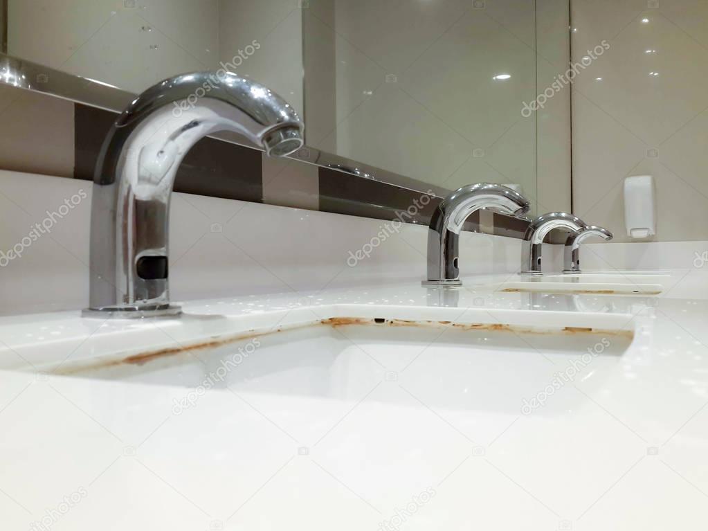 many steel taps in white ceramic sink
