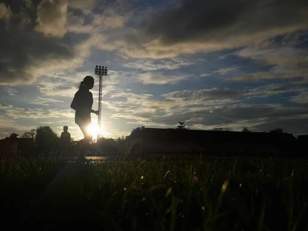 Silueta běžící na silnici při východu slunce. — Stock fotografie