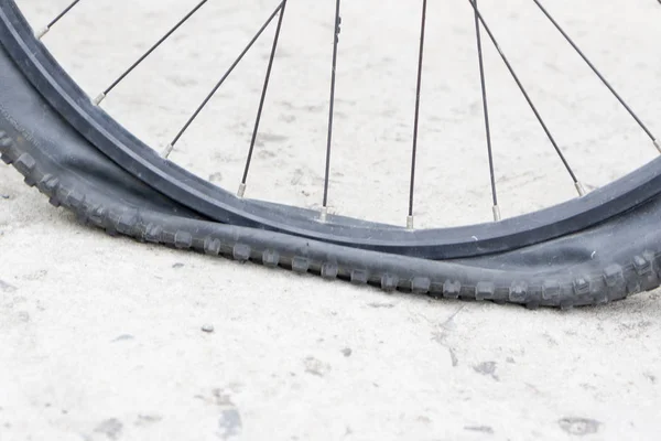 Bicycle wheel with flat tyre on the concrete road.