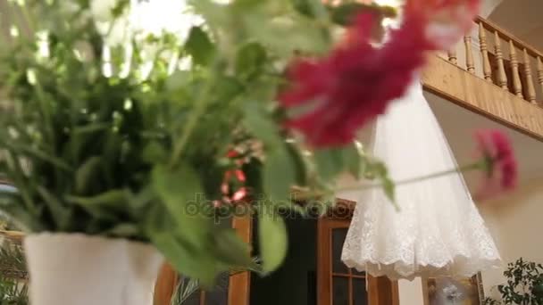 完璧なウェディング ドレスの花嫁にブルーのカーテンの部屋でハンガーに完全なスカート — ストック動画