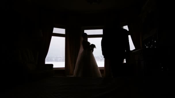 Silhouet van een bruid en een bruidegom op de achtergrond van een venster — Stockvideo