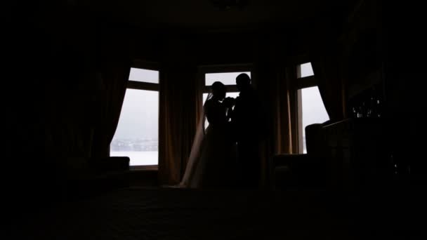 Silhueta de uma noiva e noivo no fundo de uma janela — Vídeo de Stock