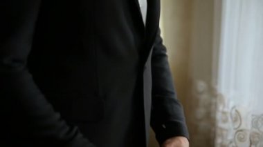 Yakın çekim adam arka plan ayakta iken onun ceket düğmesi ayarlama