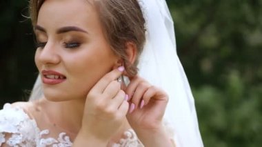 Güzel saçlı tatlı gelin üzerinde küpe çeker.