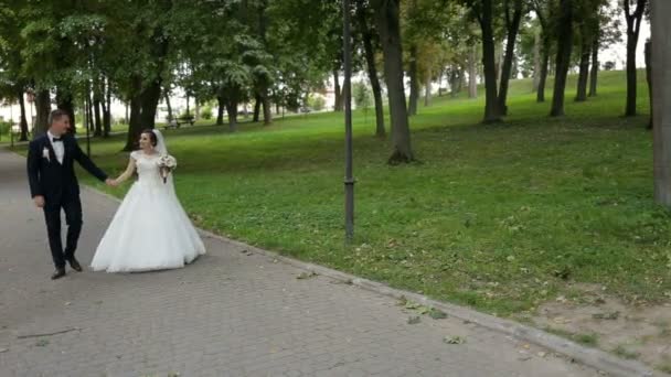 Счастливая невеста и жених гуляют в парке . — стоковое видео