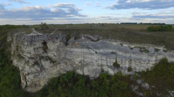 Великий захід сонця на озері між горами. Пара обіймається на краю скелі. 4k — стокове відео