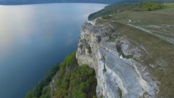 Grande pôr do sol no lago entre as montanhas. Um casal abraçado na beira do penhasco. 4k — Vídeo de Stock