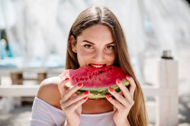 Güzel kız sahilde bungalovda karpuz yiyor.