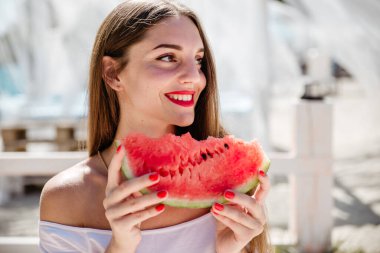 Güzel kız sahilde bungalovda karpuz yiyor.
