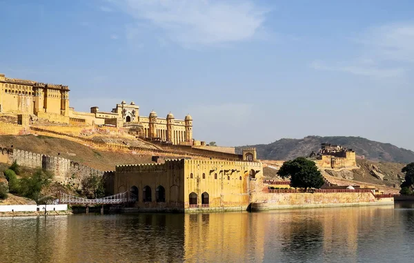 Veduta di parte dell'antico forte di Ambra, mura, porte e edificio adiacente con ponte dal lago Maota. Jaipur, India . Immagine Stock