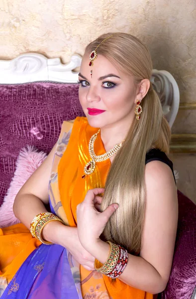 Young woman with long blond hair in a bright Indian saris and jewelery looking directly at the viewer — Stock Photo, Image