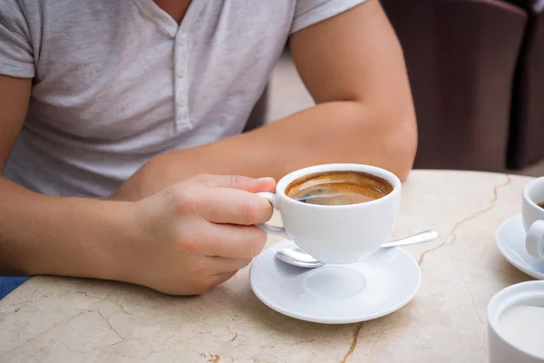 Man at marble table holds cup of americano coffee