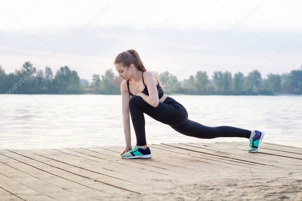 Young woman stretches her legs during training workout exercises