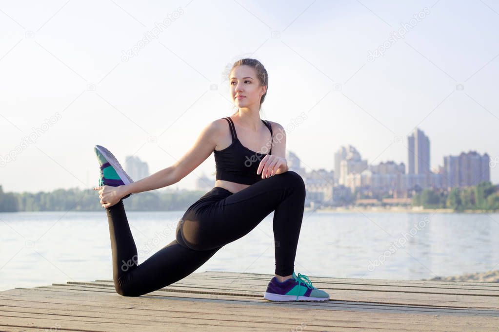 Young girl stretches her legs during sport workout exercises out