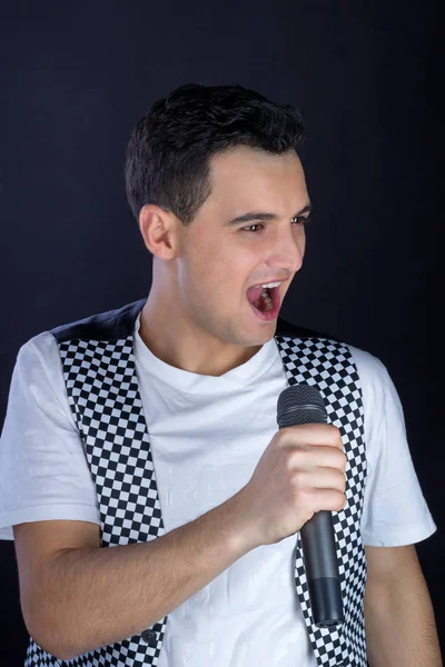Young male black-haired pop singer singing to microphone — Stock Photo, Image