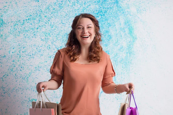 행복 한 웃는 여자 쇼핑 종이 가방을 들고 오렌지 블라우스 — 스톡 사진