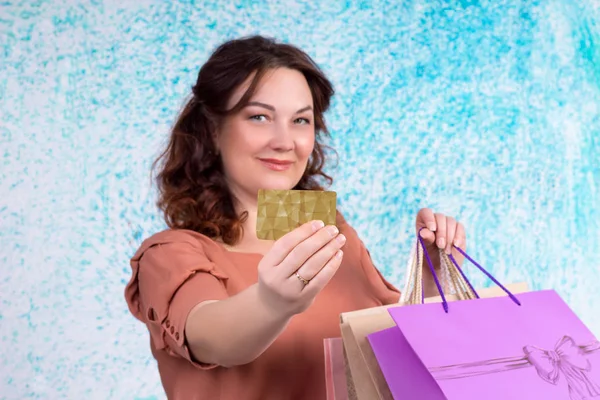 Χαμογελαστή γυναίκα με πολύχρωμες τσάντες αγορών χαρτί δείχνει τραπεζικές c — Φωτογραφία Αρχείου