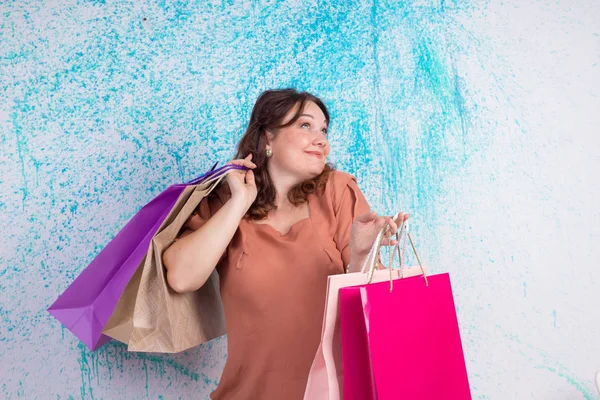 Ευτυχισμένη γυναίκα χαμογελαστή στο εμπορικό κατέχει πολύχρωμες χάρτινες σακούλες, συσκευασία πλασ — Φωτογραφία Αρχείου