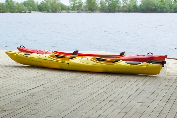 Dos barcos de kayak en cubierta de madera en la estación cerca del agua — Foto de Stock