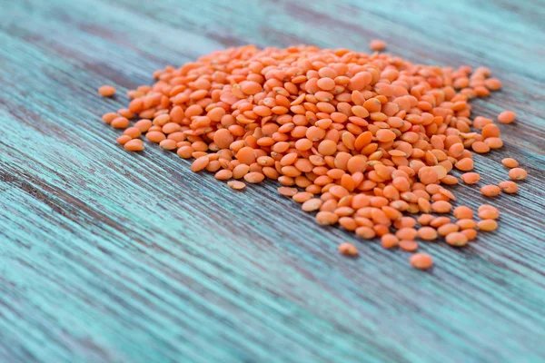 Orange lentils batch scattered on light wooden background — Stock Photo, Image