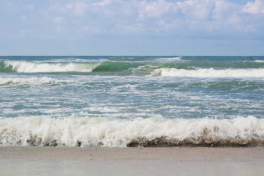 Boş kumsalda inişli çıkışlı dalgalar deniz sahil fırtınalı bulutlu gündoğumu