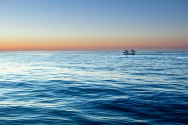 Dramatik sakin berrak gökyüzü ile açık denizde gündoğumu günbatımı