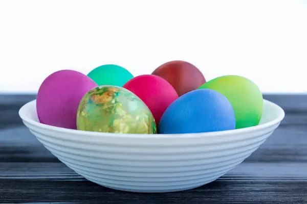 White plate with Easter multicolored boiled eggs on black wood — Stock Photo, Image