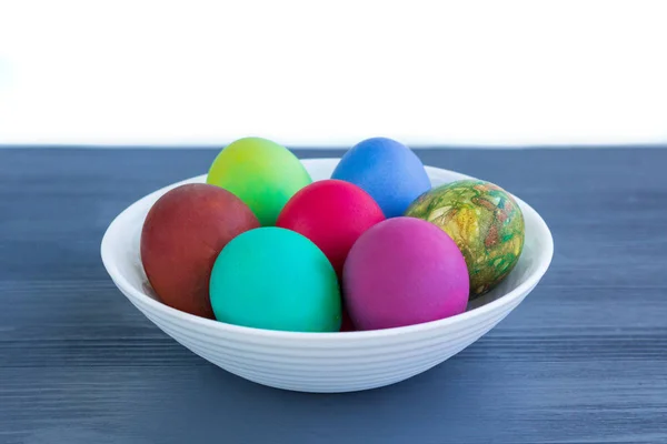 White plate of Easter versicolored eggs on grey wood — Stock Photo, Image