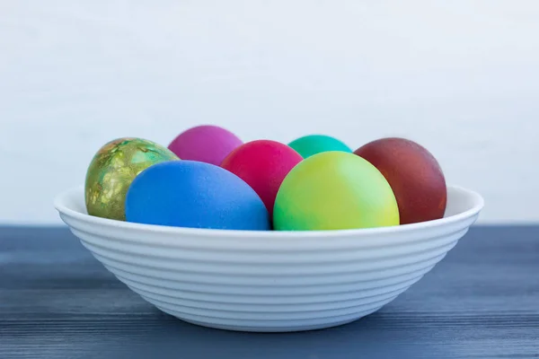 White plate wit Easter versicolored boiled eggs on grey wood — Stock Photo, Image