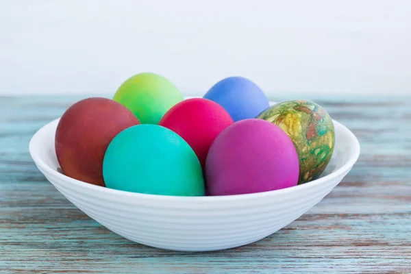 Λευκό πιάτο με πολύχρωμα Πασχαλινά βραστά αυγά στο ξύλινο backg — Φωτογραφία Αρχείου