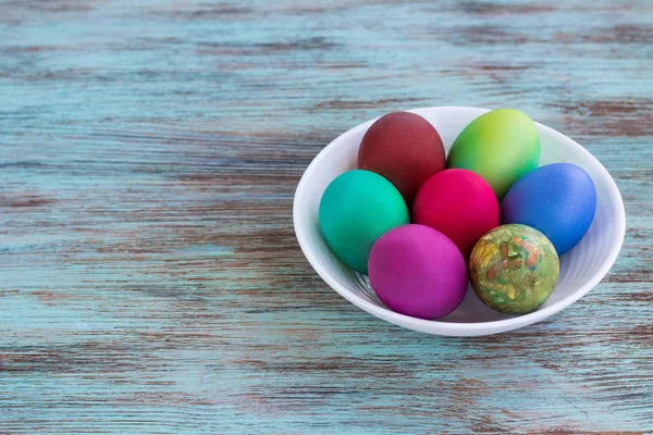 White plate of Easter versicolored eggs on wooden background — Stock Photo, Image