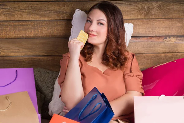 Женщина после покупок на кровати с бумажными пакетами, банковской картой — стоковое фото