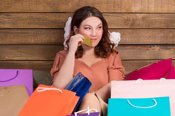 Žena po nakupování na posteli s papírové sáčky, bankovní karta — Stock fotografie