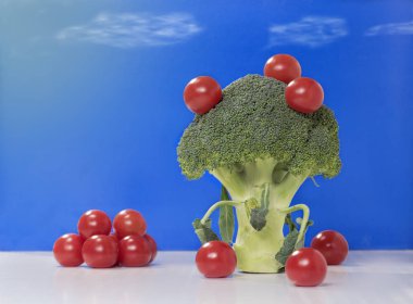 Natürmort brokoli ve mavi bir arka plan üzerinde kiraz domates ile.