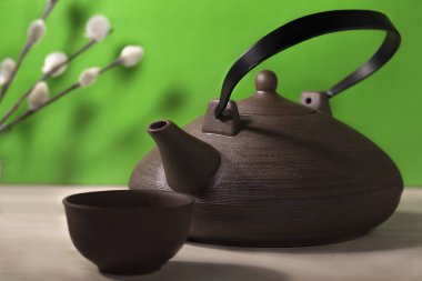 Yeşil zemin üzerine ahşap masa üzerinde Çince çaydanlık ile natürmort.