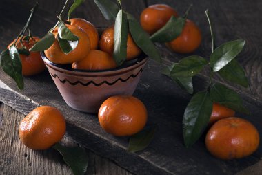 Seramik vazo içinde ve ahşap bir masa üzerine mandalina yalan.