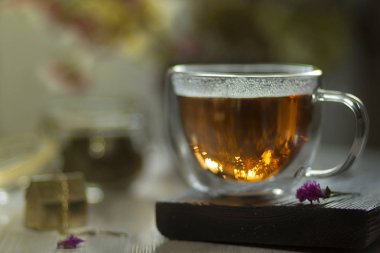 Bir fincan çay masaya camdır. Çiçekler içinde belgili tanımlık geçmiş.