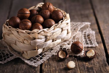Tahta bir masada hasır bir sepetin içinde bir grup Macadamia fındığı..