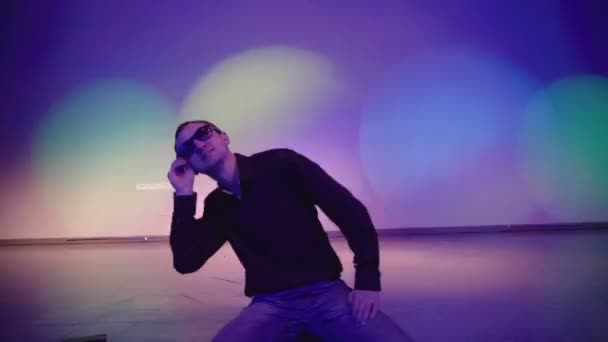 Очень крутой тусовщик в солнцезащитных очках, танцующий один в ночном клубе — стоковое видео