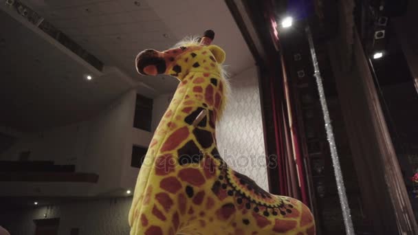 Игрушечный жираф стоит на театральной сцене — стоковое видео