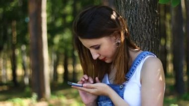 Kadın bir smartphone parkta kullanır.