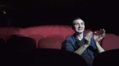Rahat kırmızıyla oturan adam karanlık sinema tiyatroda sandalyeler ve alkışlar