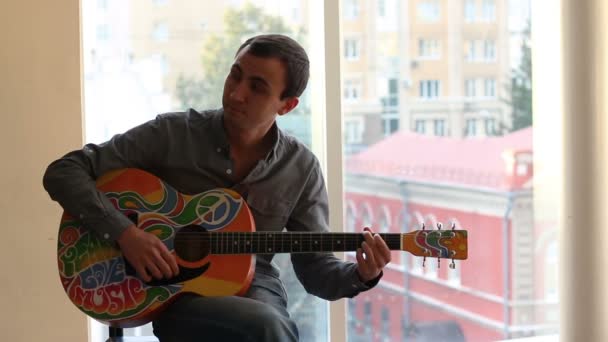 Jovem atraente homem toca guitarra pintada em estilo hippie — Vídeo de Stock