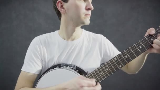 Young guy plays the banjo. Black background — Stock Video